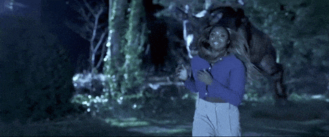 a woman in a blue shirt is running from a deer
