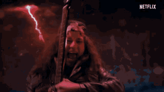 a man holding a guitar in front of a red lightning bolt and a netflix logo