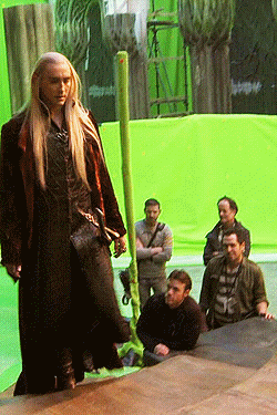 a man with long blonde hair is standing in front of a green background