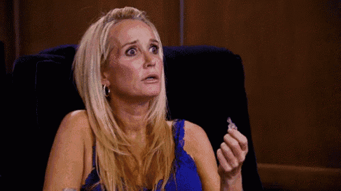 a woman in a blue tank top is sitting in a chair holding a ring in her hand .