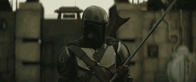 a man in a helmet is holding a spear and looking at the camera