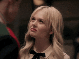 a woman with blonde hair and a black bow tie looks up at something