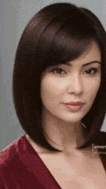 a close up of a woman 's face with a bob hairstyle and a red shirt .