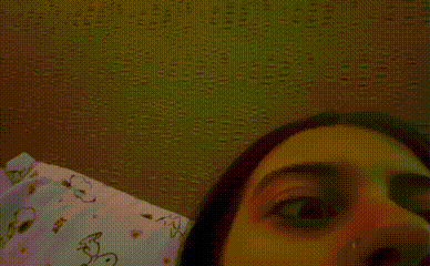 a close up of a woman 's face with a patterned wall behind her