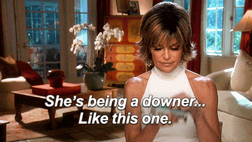 a woman is sitting in a living room with the words she 's being a downer like this one