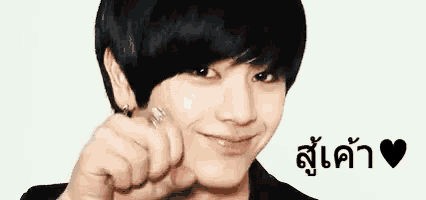 a young man is pointing at the camera with his fist .