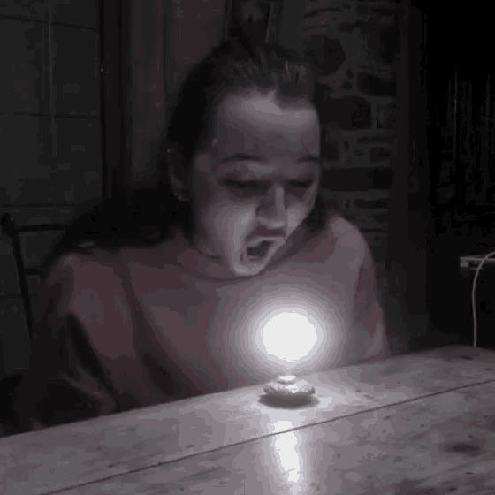 a girl in a red sweater is sitting at a table with a light on .