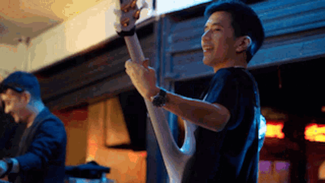 a man in a black shirt is playing a white guitar