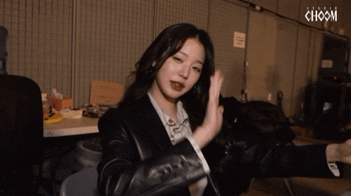a woman wearing a black jacket with the word choom on the bottom left