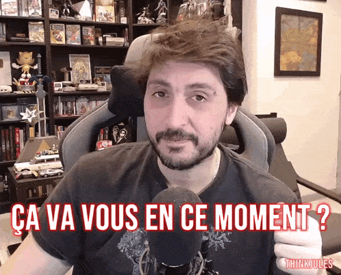a man is sitting in front of a microphone with the words ca va vous en ce moment