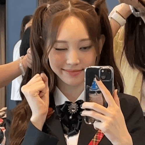 a woman in a school uniform is taking a picture of herself in the mirror with her phone .