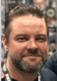 a man with a beard is smiling for the camera while wearing a lanyard .