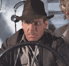 a man wearing a hat and a jacket is behind the wheel
