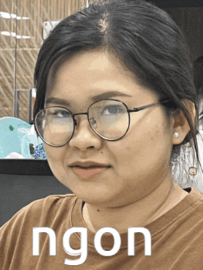 a woman wearing glasses and a brown shirt with the word ngon written on it