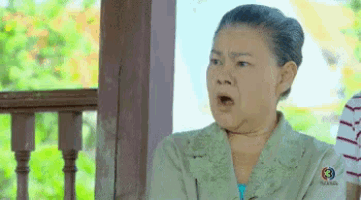 an older woman is sitting on a porch making a funny face .