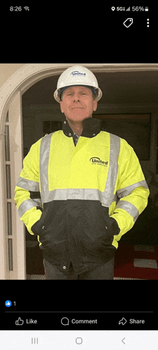a man wearing a hard hat and a united jacket stands in a doorway