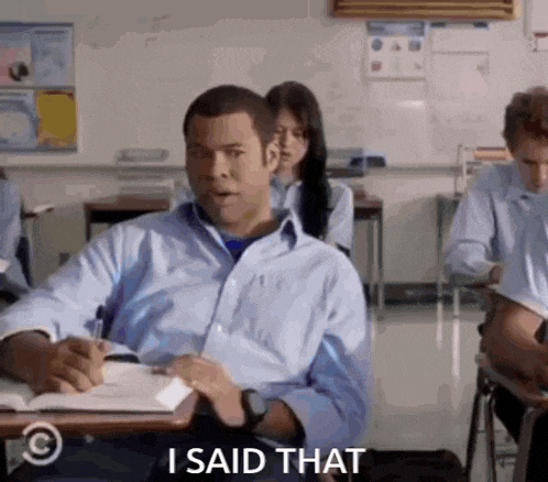 a man is sitting at a desk in a classroom and saying " i said that "