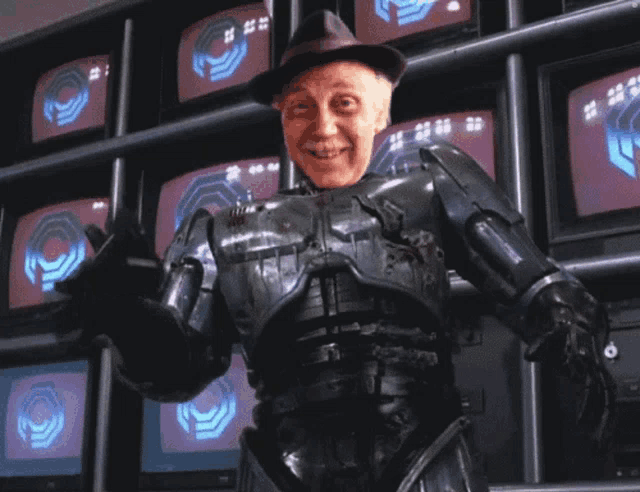 a man in a robot costume is standing in front of a wall of monitors