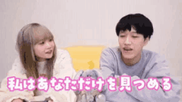 a man and a woman are sitting next to each other on a couch and talking in japanese .