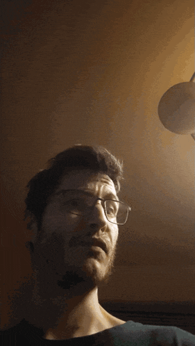 a man with glasses and a beard is looking down at something