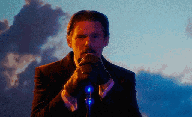 a man in a suit and gloves is holding a microphone