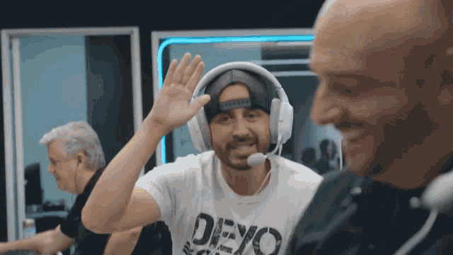 a man wearing headphones and a devo t-shirt waves
