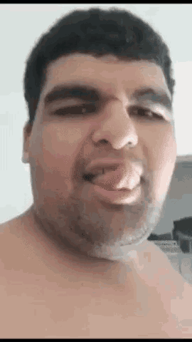 a shirtless man is making a funny face with his tongue sticking out .