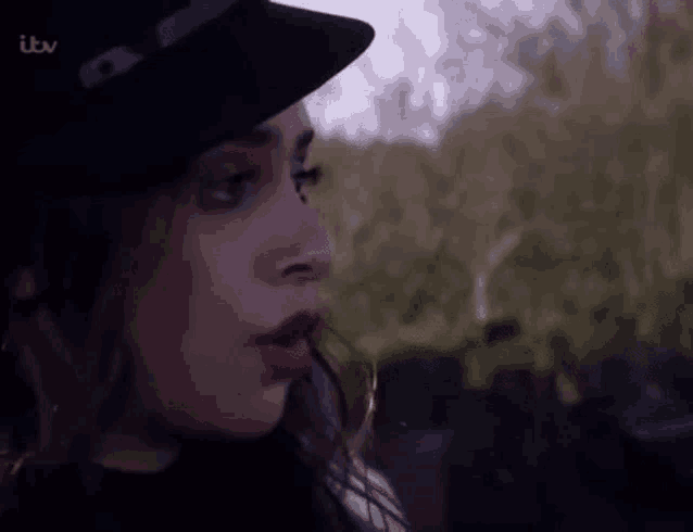 a close up of a woman 's face wearing a hat and lipstick .