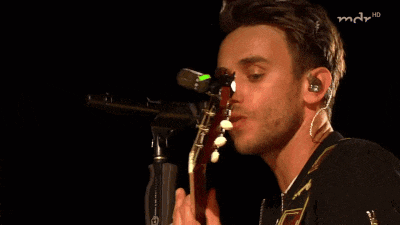 a close up of a man singing into a microphone with a green light on it