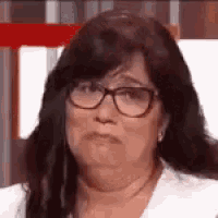 a close up of a woman wearing glasses and a white shirt .