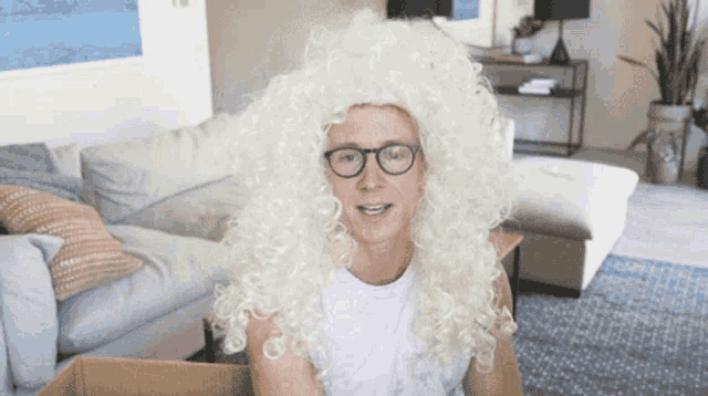 a man wearing a white wig and glasses looks at the camera