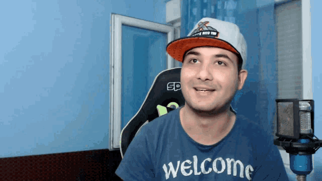 a man wearing a blue shirt that says welcome on it