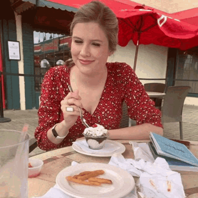 a woman is sitting at a table eating ice cream with a spoon