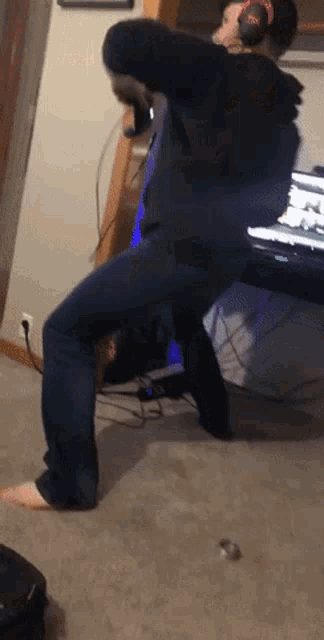 a man wearing headphones stands on one leg in front of a desk