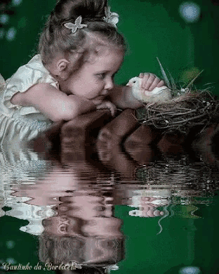 a little girl is holding a chicken in a nest