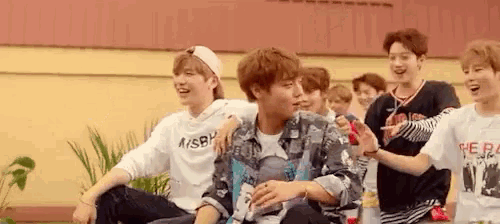 a group of young men are sitting next to each other on a bench and laughing .