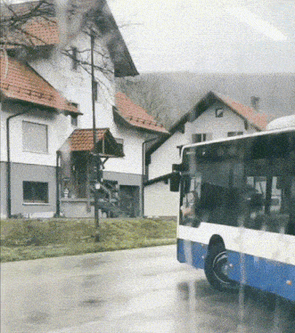 a blue and white bus is driving down a wet road