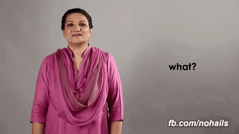 a woman in a pink shirt is making a gesture that says what .