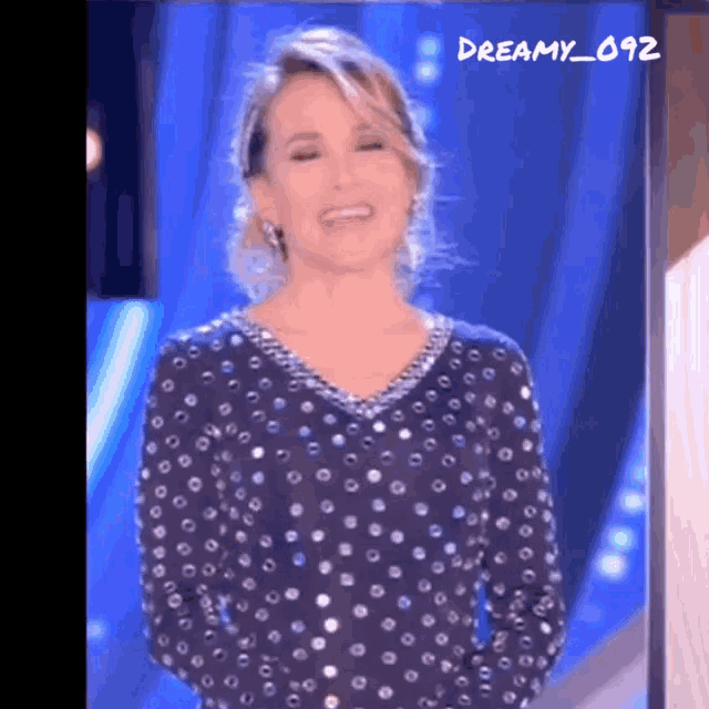 a woman in a polka dot dress is smiling in front of a blue background with dreamy_092 written on it