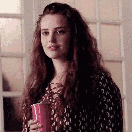 a woman is standing in front of a door holding a pink cup .