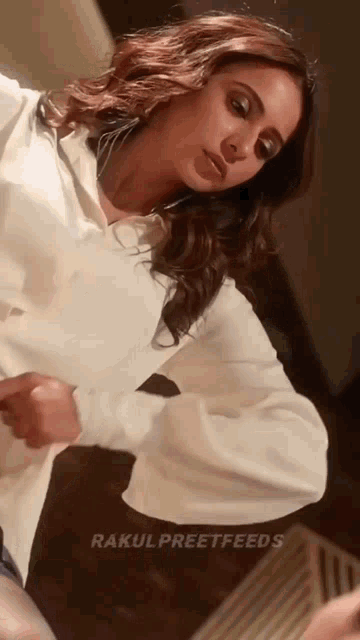 a woman in a white shirt looks at herself in a mirror