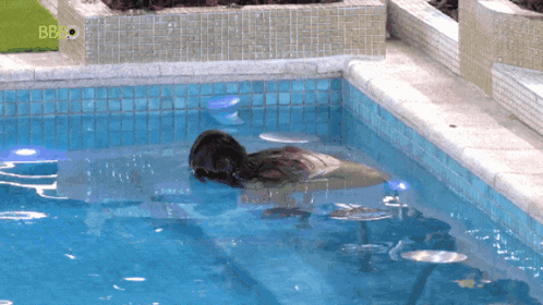 a woman is floating in a swimming pool with the bbc logo visible