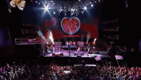 a group of people playing instruments on a stage in front of a large crowd