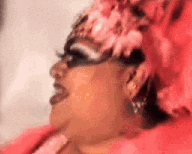 a close up of a woman wearing a pink feathered hat and earrings