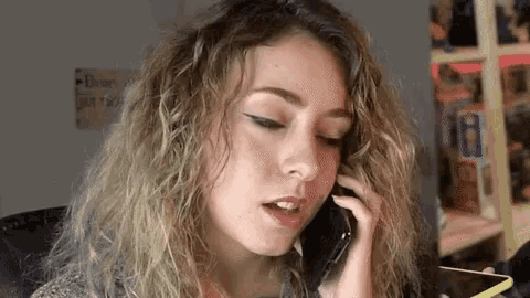 a woman is talking on a cell phone while looking at her phone .