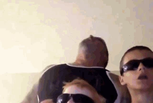 a man and a boy wearing sunglasses are sitting next to each other on a bed .