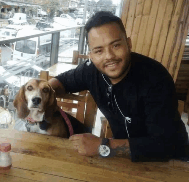 a man is sitting at a table with a dog on his lap