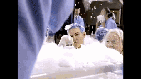 a group of people are taking a bath with foam on their faces