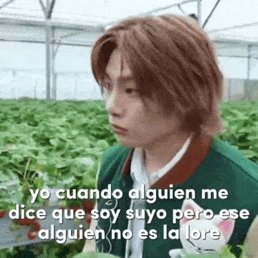 a young man in a green jacket is standing in front of a greenhouse with a caption in spanish .