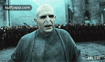 a man with a bald head is standing in front of a crowd of people .